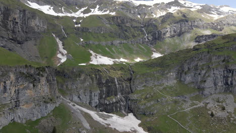 high aerial flying towards alpine mountain range showing multiple steams of water running down to the valley in a remote landscape