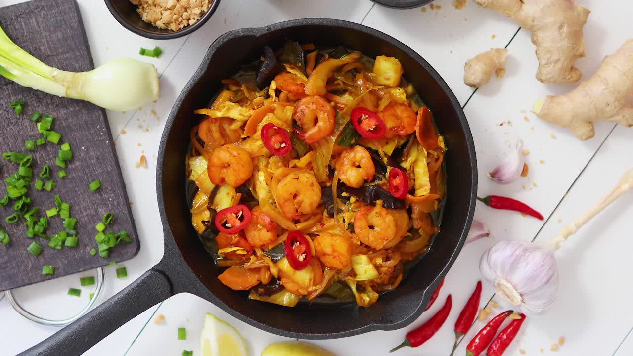 fideos fritos frescos con verduras con camarones servidos en una sartén de hierro negro con varios ingredientes