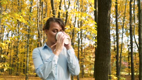 woman with coffee in park. young woman relaxing with cup of coffee in park