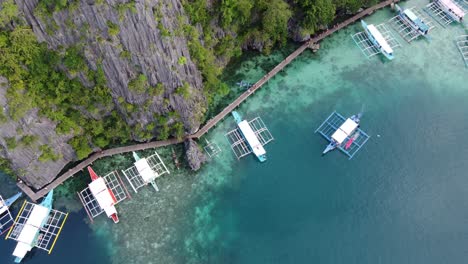 barcos de salto de isla cargando turistas en el muelle del lago kayangan, descendiendo drones de arriba hacia abajo