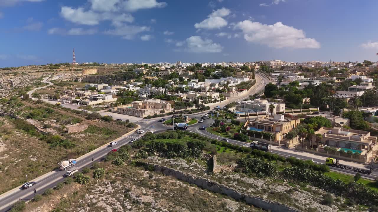 Revealing aerial view from the entering roundabout towards the residential townscape of Naxxar on a sunny autumn day in Malta