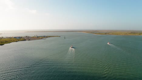 Sobrevuelo-De-Drones-Aéreos-De-Barcos-Que-Salen-De-La-Entrada-Del-Puerto-De-La-Bahía-En-La-Isla-Del-Padre-Sur,-Costa-De-Texas