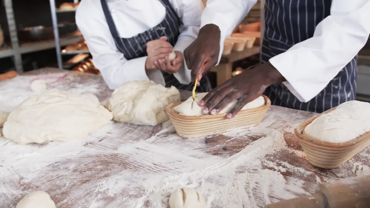 Diversi panettieri al lavoro in una panetteria, che tagliano l'impasto per il pane al rallentatore.