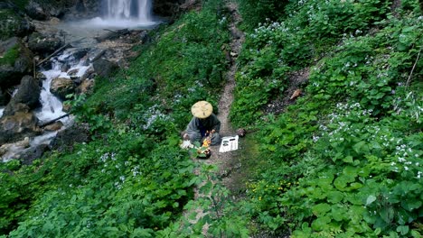 man with beard makes fire ceremony in front of big waterfall