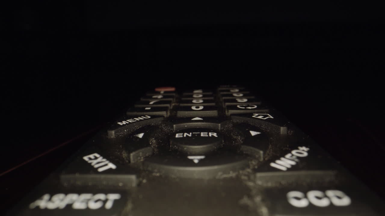 더러운 tv 리모콘의 극도로 가까운 돌리 - 버튼 사이에 먼지와 먼지가 보입니다.