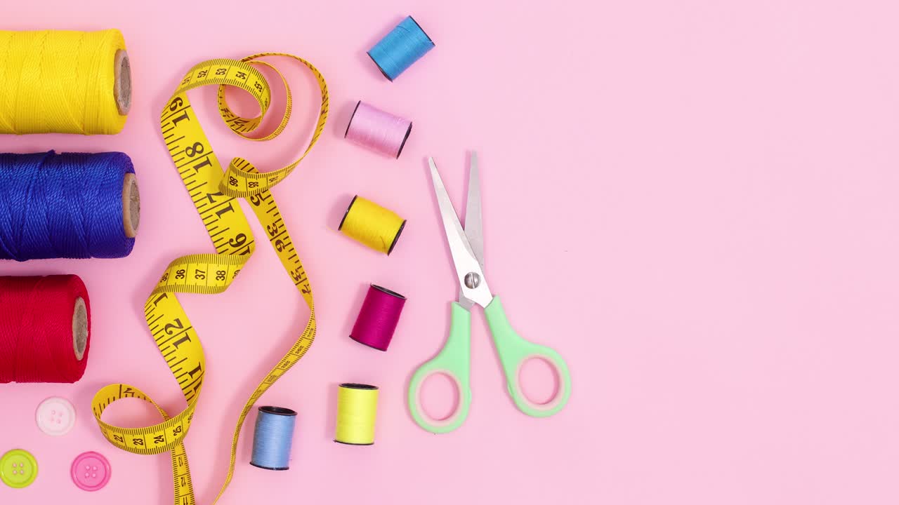 los artículos de costura de artesanía creativa se mueven en un fondo rosa pastel con espacio de copia.