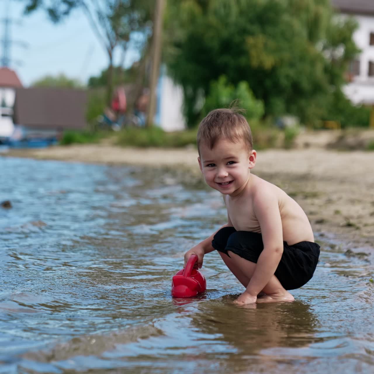 Little funny boy playing on a river beach. Water playing with splashing