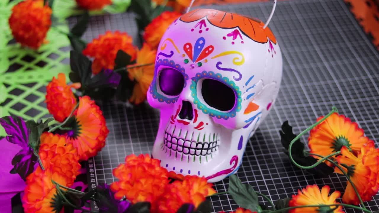 Colorful Day of the Dead skull candy bucket surrounded by marigolds