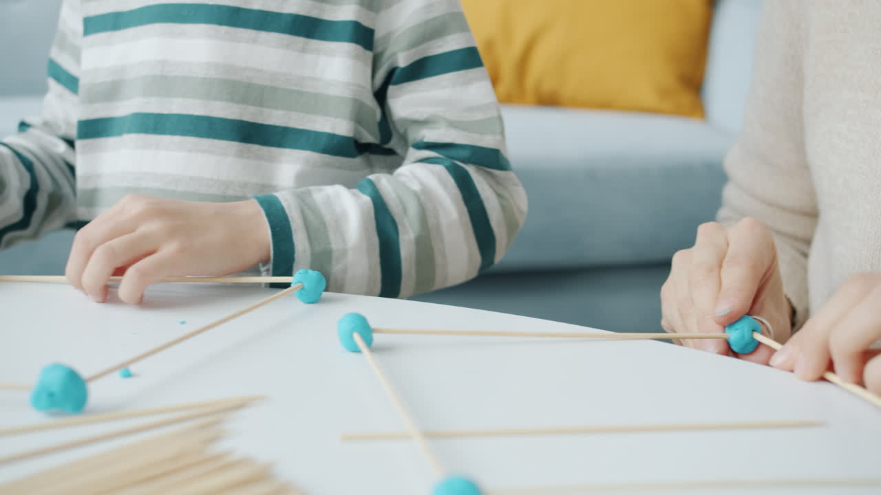 Child and adult playing with playdough and sticks