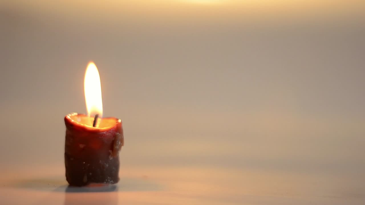 Una sola candela tremola con riflessi.