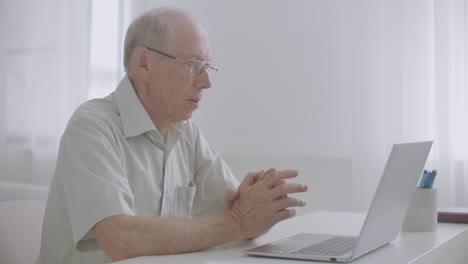 aged male experienced specialist is communicating by video call at laptop with colleagues working from home
