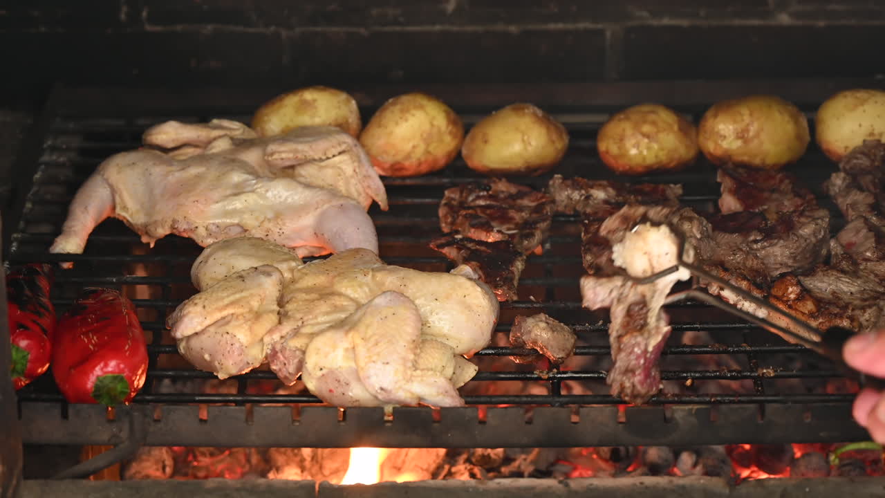 Close up of a sizzling barbecue grill filled with juicy beef steaks, seasoned chicken, and charred red peppers roasting over glowing embers
