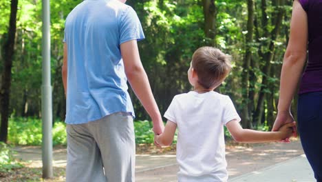una familia de tres personas está caminando en el parque 02