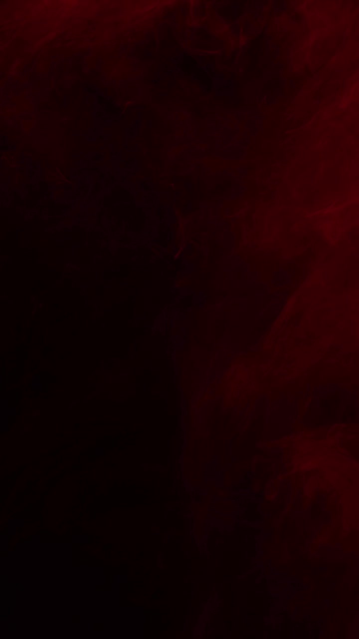 Nebbia o fumo rosso tenue e soffuso si sposta lentamente su uno schermo scuro. Sovrapposizione atmosferica per creare un'atmosfera cupa, horror o drammatica, VFX, formato verticale