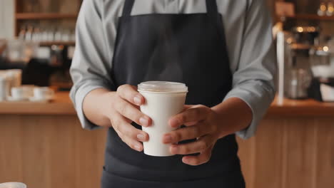 barista handing over a takeaway coffee cup