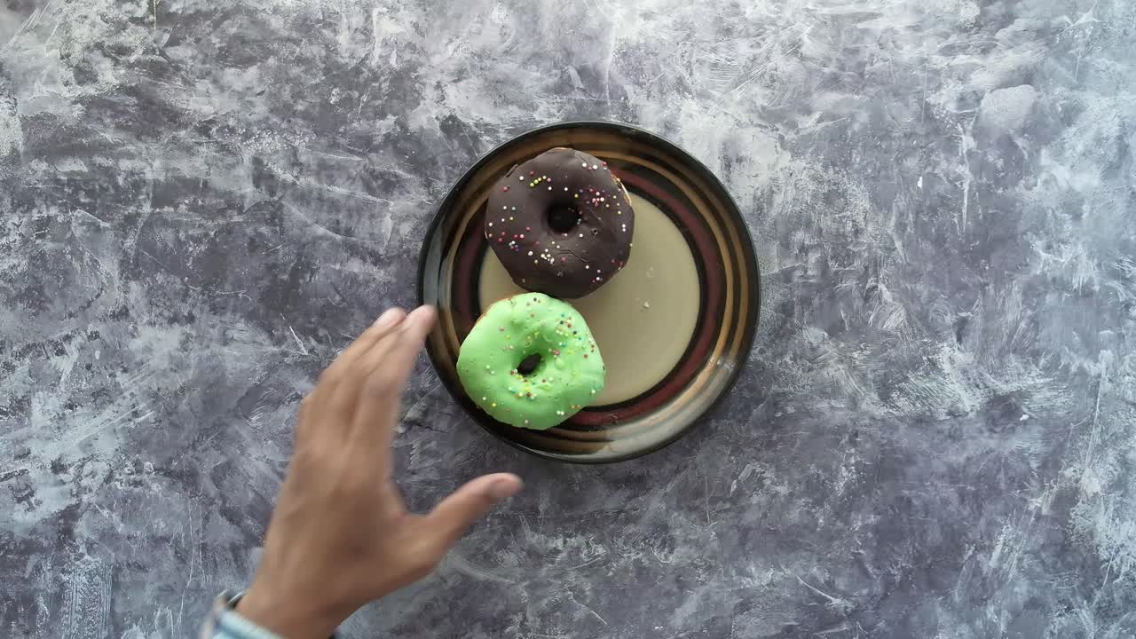 Mano che prende ciambelle da un piatto