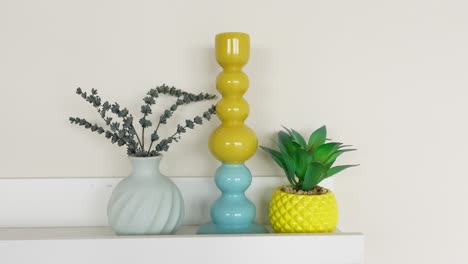 colorful vase and plant arrangement on a white shelf