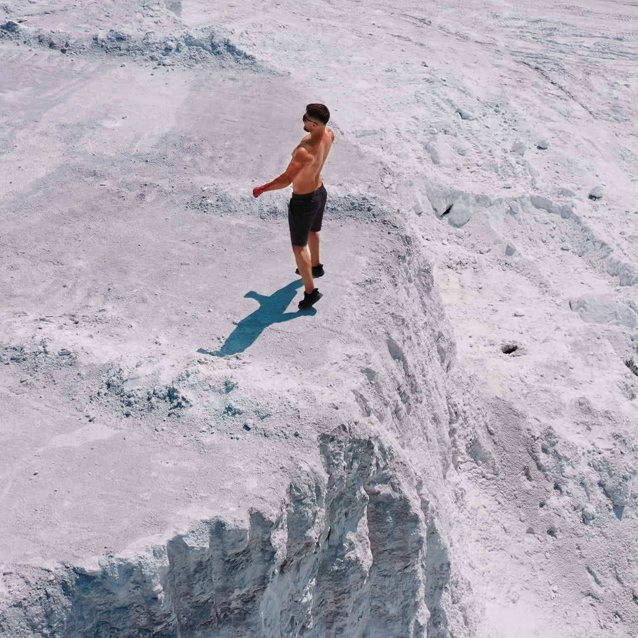 Brutal strong bodybuilder pumping up muscles. Bodybuilding and outdoor sports concept. Posing outdoor. Training in a quarry. Aerial view. White landscape.