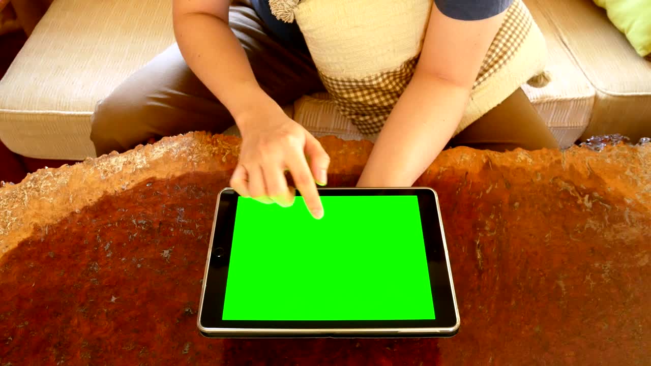 man hand using digital tablet computer with mock up green screen for chroma key in living room - indoor scene