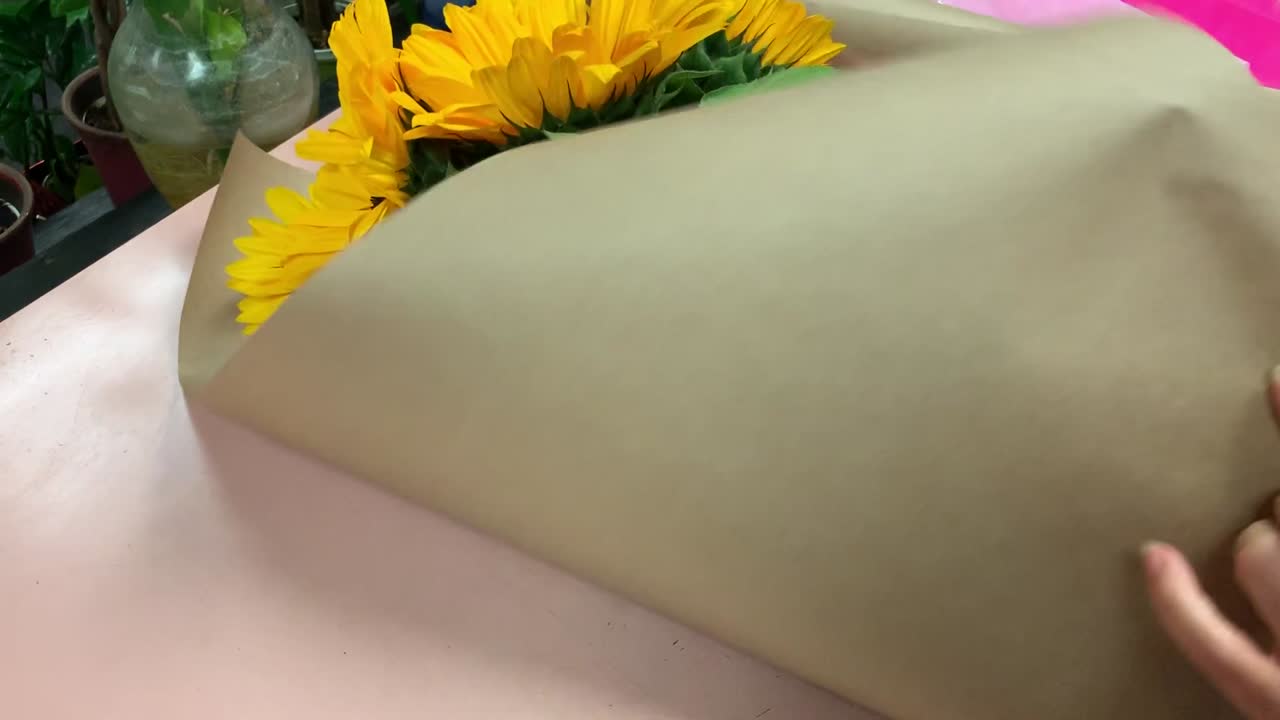 una floristería local envolviendo un ramo de girasoles recién cortados con papel de carnicero marrón