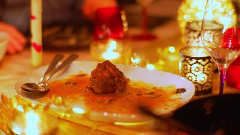 leftover of lamb meat on a plate in between candles during party