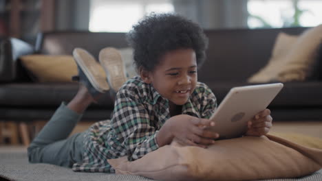 little afro boy chilling at home with digital tablet