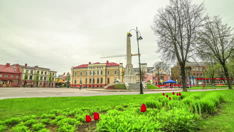 Ascending-Timelapse-of-Victory-Monument-amongst-tulip-garden,-Cesis,-Latvia