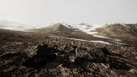 snow covered rocky hill in middle of desert on cloudy day