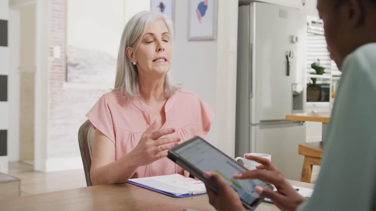 mujer caucásica mayor feliz con amiga afroamericana usando una tableta