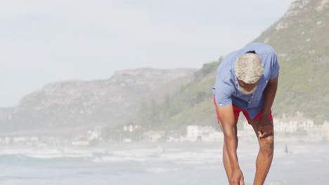 un hombre afroamericano mayor caminando solo en una playa soleada