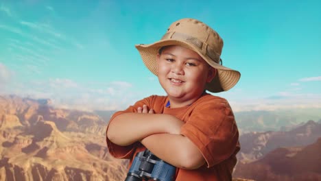 asian boy with a hat and binoculars crossing arms and smiling to camera while traveling at the top of mountain. boy researcher examines something, travel adventure, close up side view
