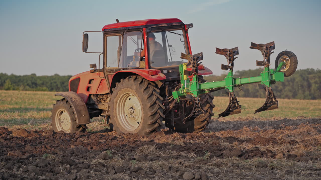 Tractor plowing land. View of red tractor in the agricultural field