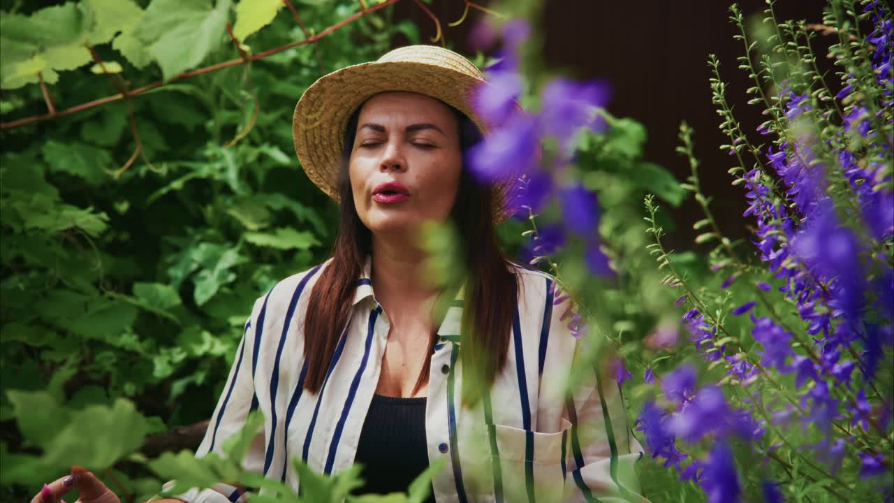 Woman in garden wearing straw hat, enjoying peaceful moment among vibrant flowers and greenery