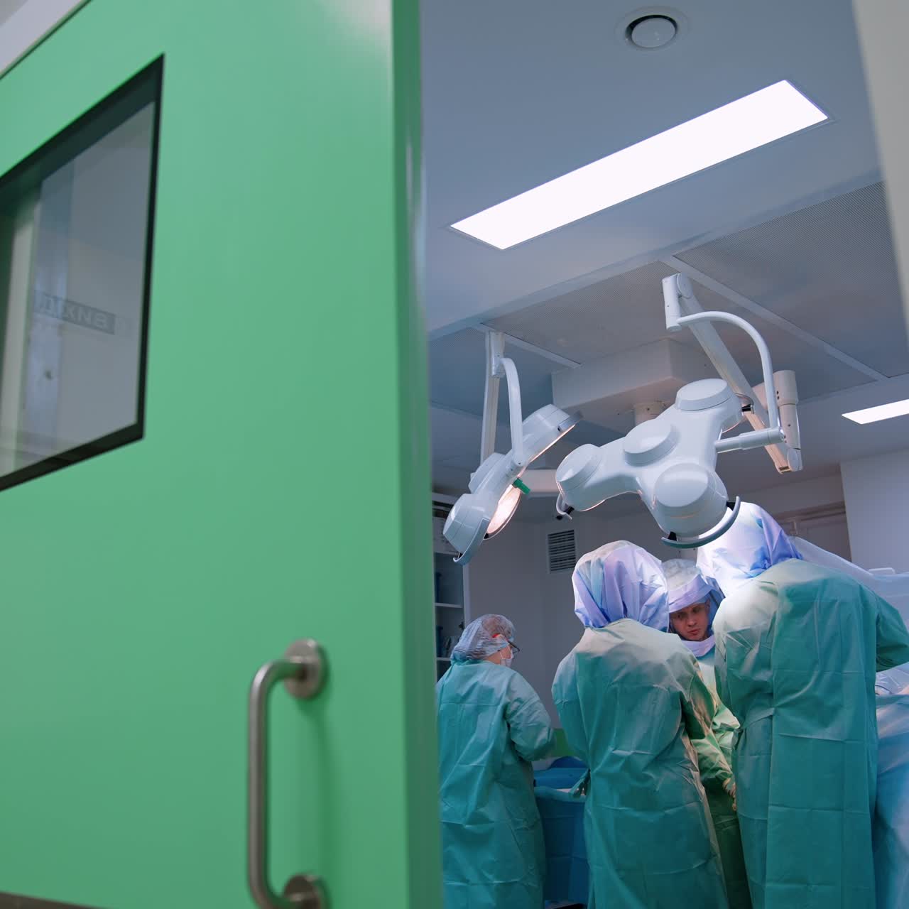 Footage at the opened doors to a modern surgery room. Medical team working at operational table. Low angle view