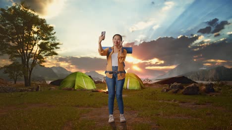 happy woman taking selfie at campsite
