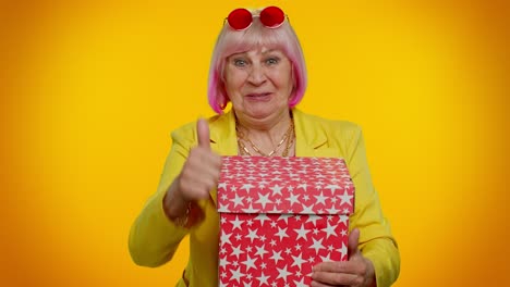 cheerful senior grandmother woman opening gift box and smiling joyfully, satisfied with nice present