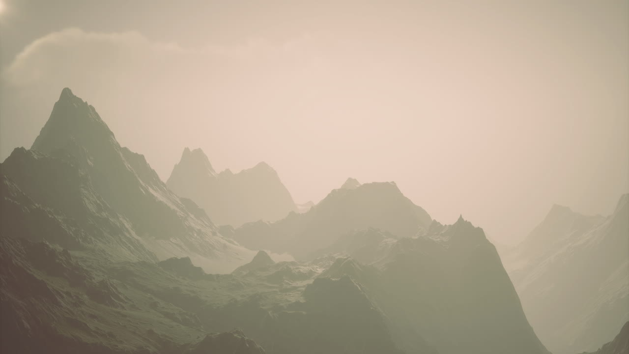 Majestic mountain range under a soft hazy sky during sunrise