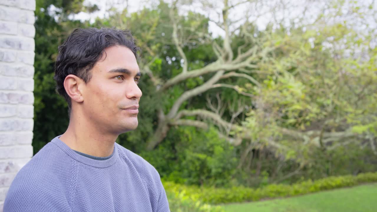 Noticing off-camera cue, male scanning patio then smiling at camera, showing smartwatch, copy space