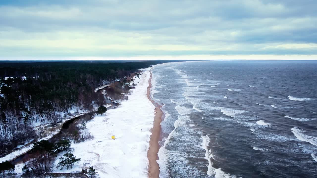 Kystlinje i blæsende vinter med bølger og sne