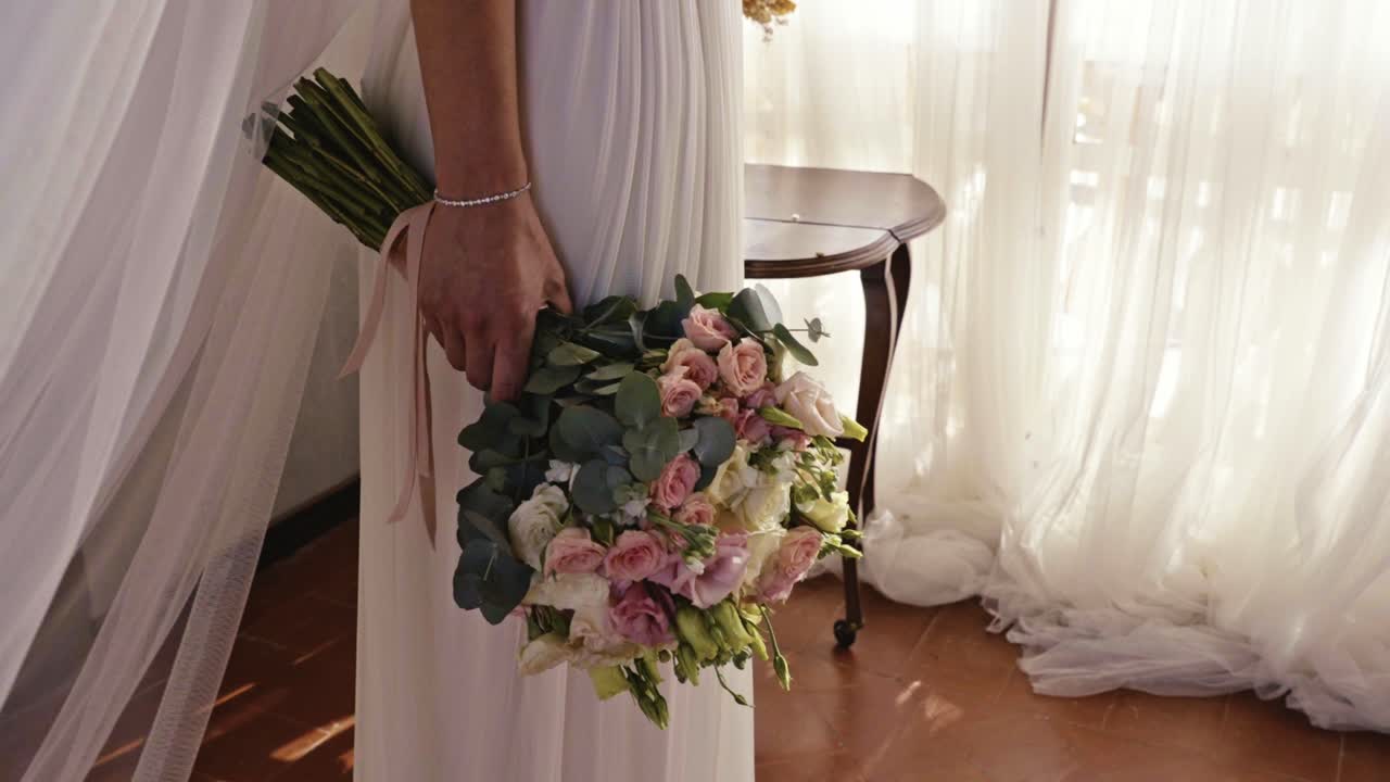 close up detail of the bride's hand before getting married holding a bouquet of flowers of various colors with lots of natural light