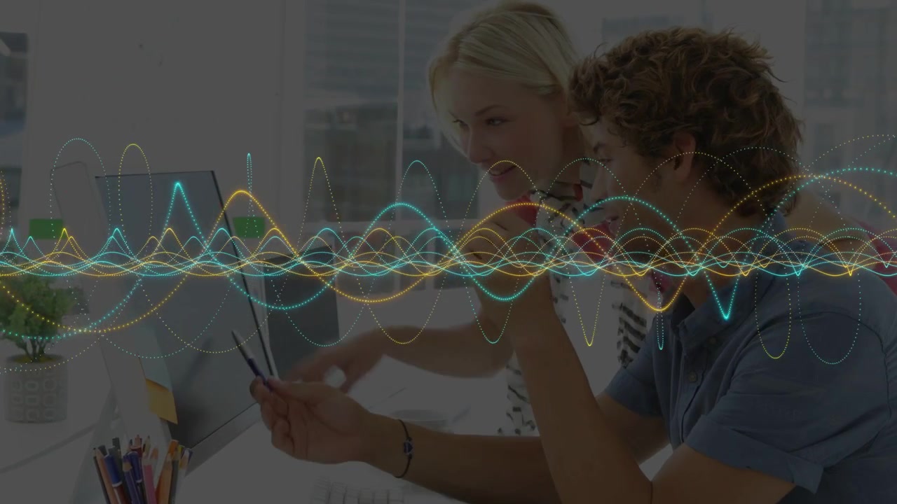 Man working at desk, woman coming and pointing phone and monitor, waveform driving business review