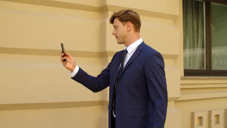 Closeup-man-talking-video-call-outside.-Male-professional-walking-at-street