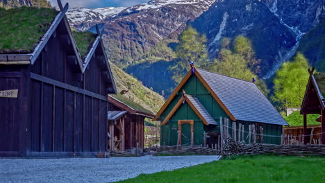 norse heritage park in norway with green-roofed wooden buildings, mountain backdrop, sunny day, timelapse