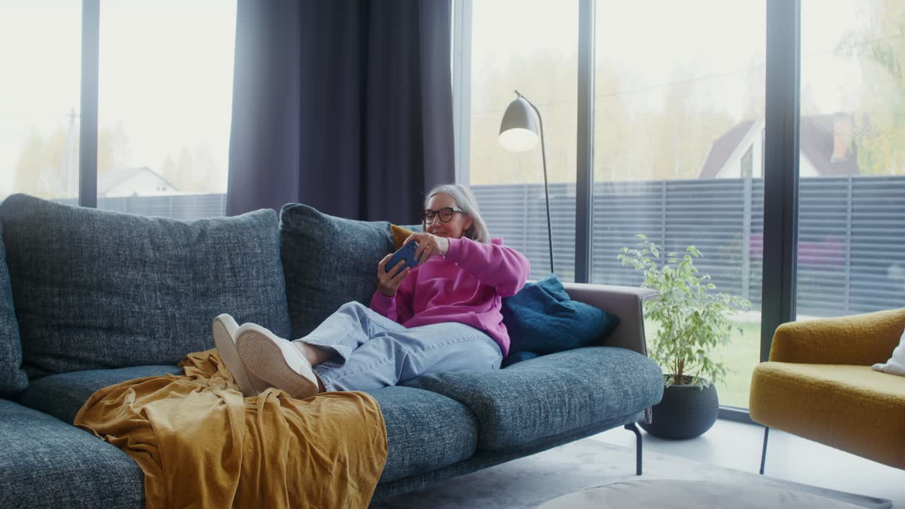 Elderly woman using smartphone on couch