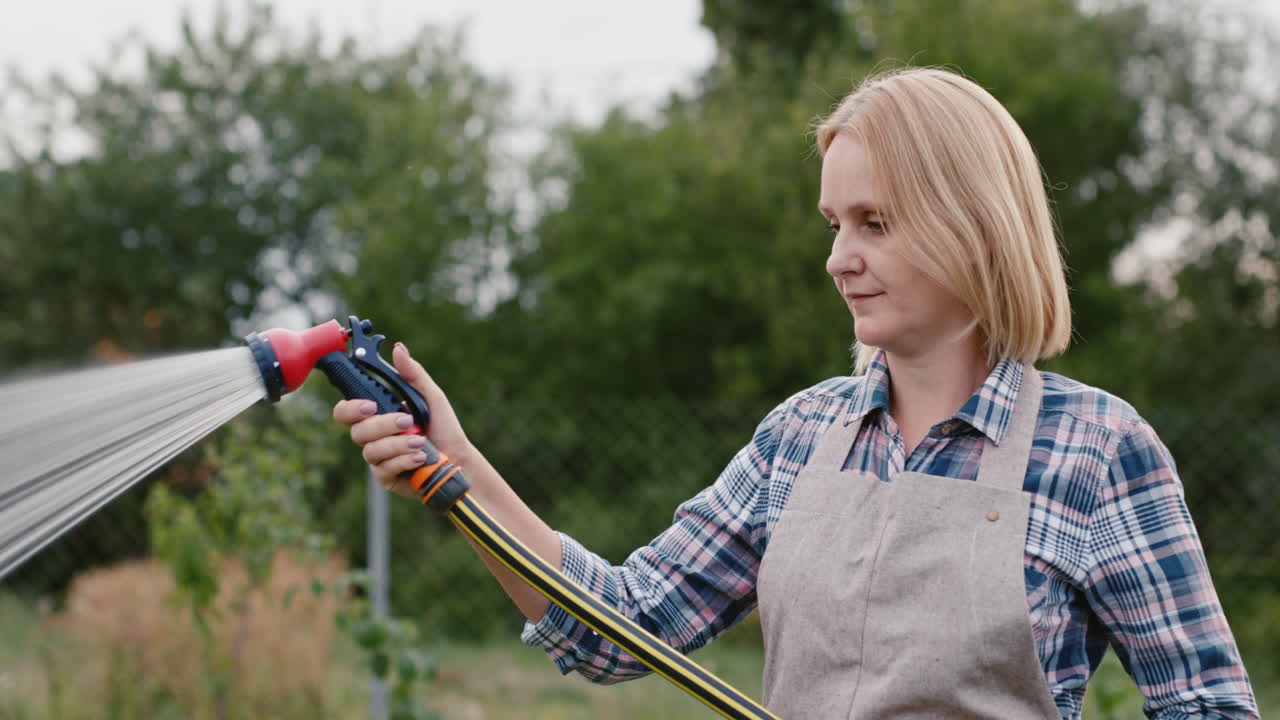 садовник поливает растения из садового шланга 2