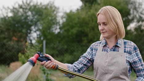 gardener waters plants from garden hose 2