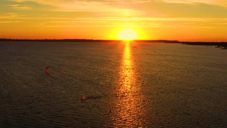 Aerial view, Kitesurfers swim at high speed in the open sea at sunset. Drone shot at three athletes on boards floating above the water surface. Poland Hel