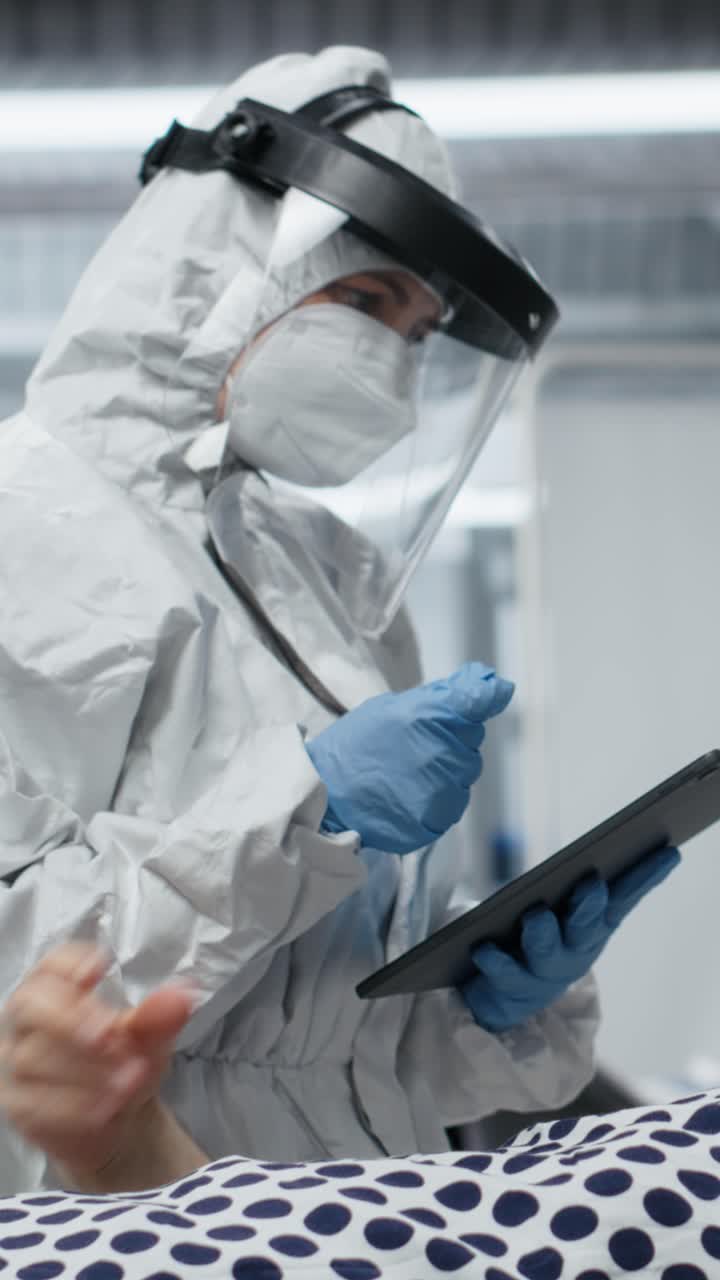 Ricercatore di video verticali con dispositivi di sicurezza che lavora in una zona a rischio biologico per curare un paziente contagioso