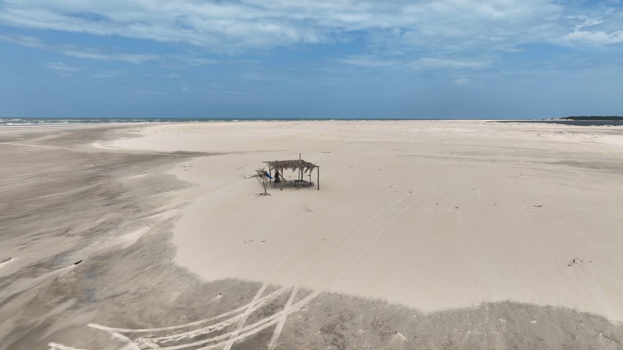Simple wooden hut on sand beach by Parnaiba River in Brazil, aerial pan