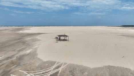simple wooden hut on sand beach by parnaiba river in brazil, aerial pan